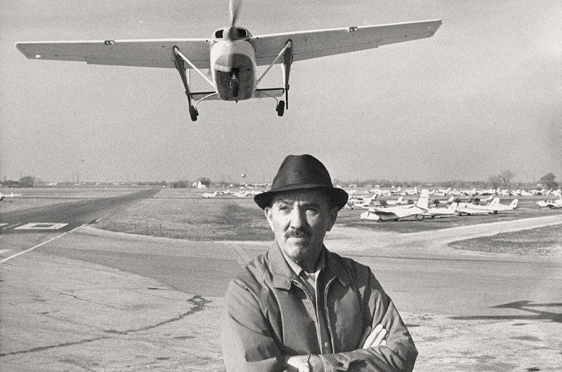 sepia photograph of man in front of airplane